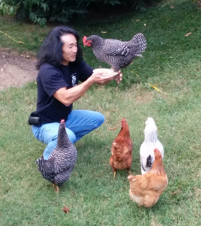 Me holding a bowl with Beatrice perched on the rim.  Other chickens look on from the ground