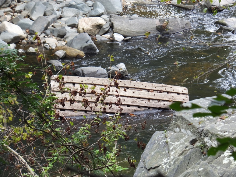 Wooden structure caught in rocks in river