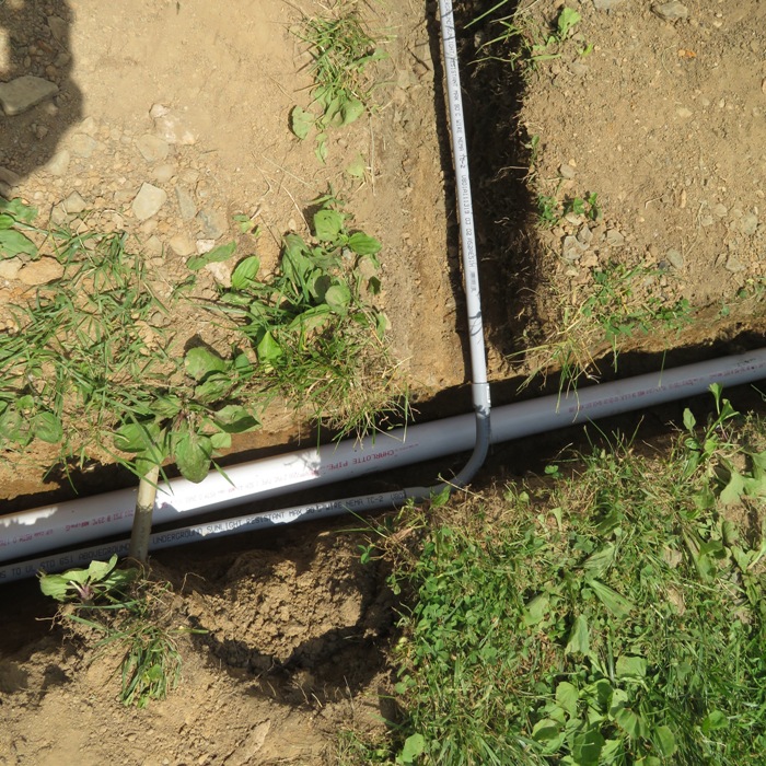 Grey conduit and white PVC in trench