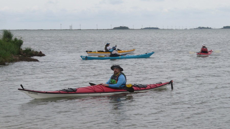 Bob in kayak with other kayakers behind and telephone poles behind them