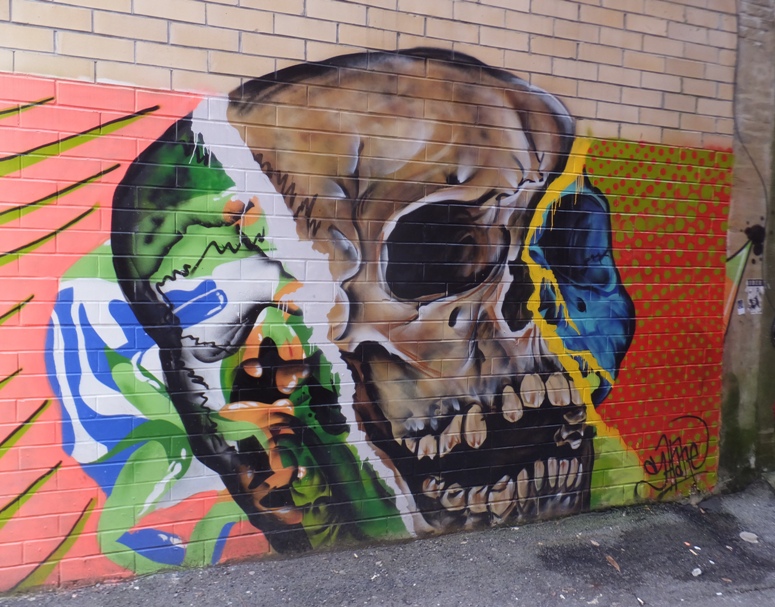 Colorful skull graffiti on brick wall