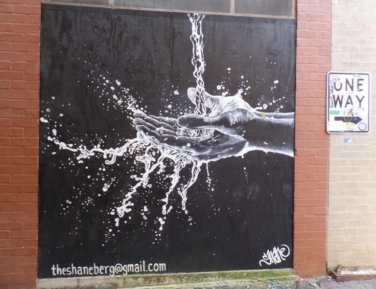 Black and white graffiti of water falling onto open hands