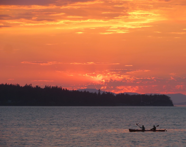 Couple in tandem kayak with clouds aglow