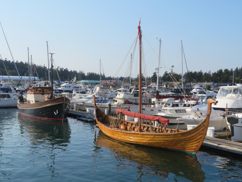 Small replica of a viking ship docked with another boat behind it