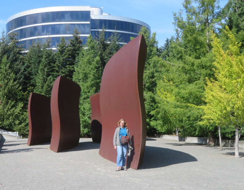 Norma in front of big, wavy, metal sculpture