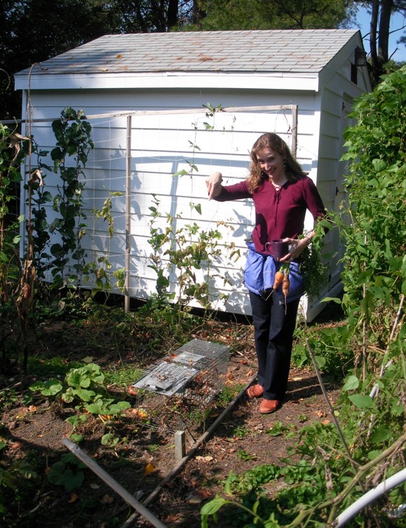 Norma in her garden, pointing to a trap