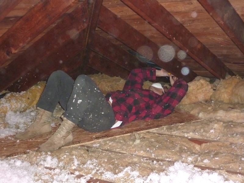 Me lying on my back in the attic, using a stapler to attach a rafter vent under the roof