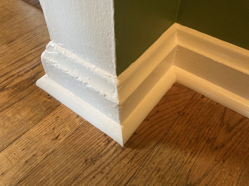 White quarter round covering gap between hardwood floor and baseboard moulding