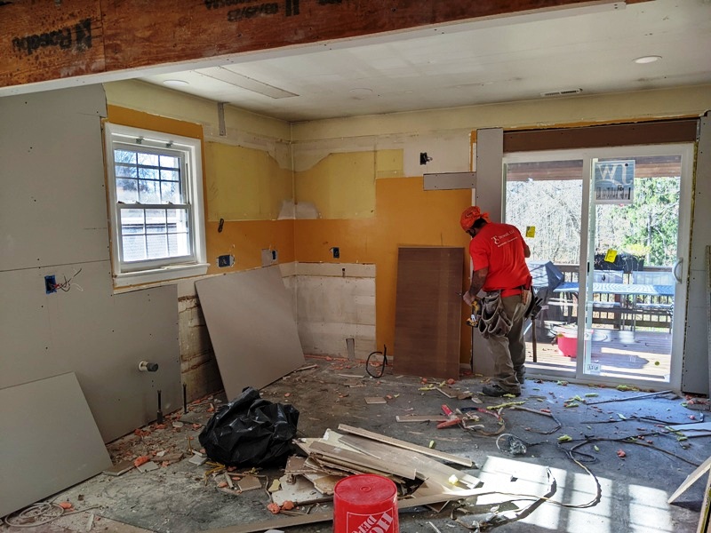 Installer with new drywall mixed with old drywall in kitchen