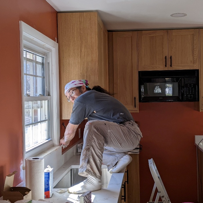 Me cleaning up area around the window above the kitchen sink