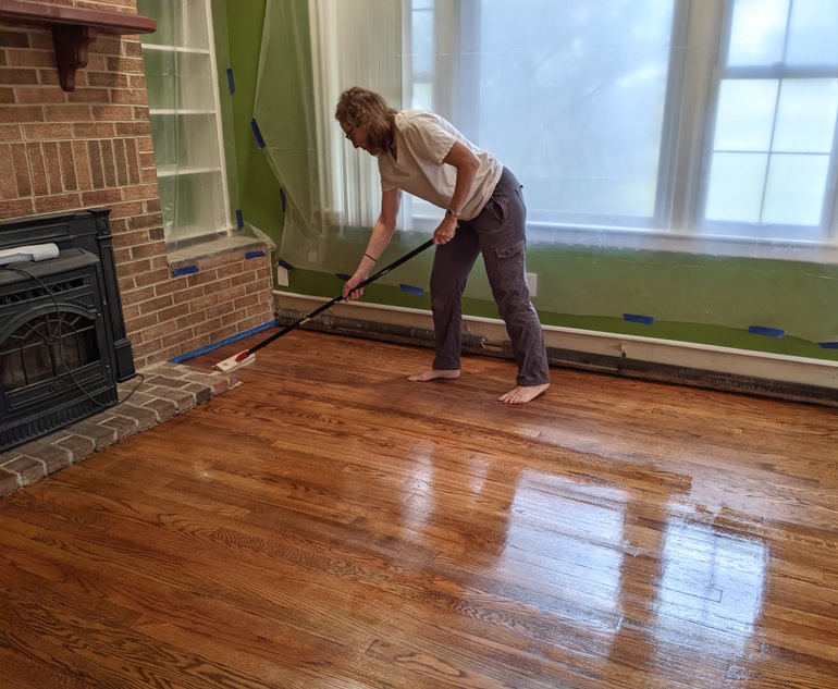 Norma applying polyurethane with an applicator at the end of a pole