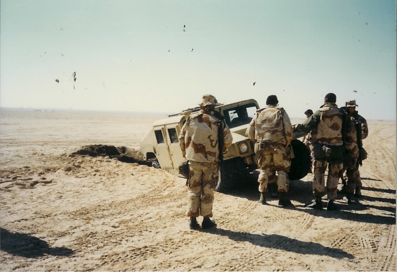 Humvee stuck in trench with Marines looking on