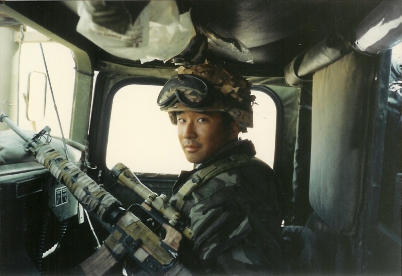 Me holding a rifle while sitting in the front passenger seat in our Humvee