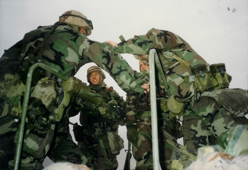 Marines huddled together, standing on a Humvee