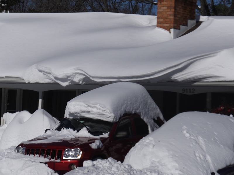 Snow-covered car under roof overhang