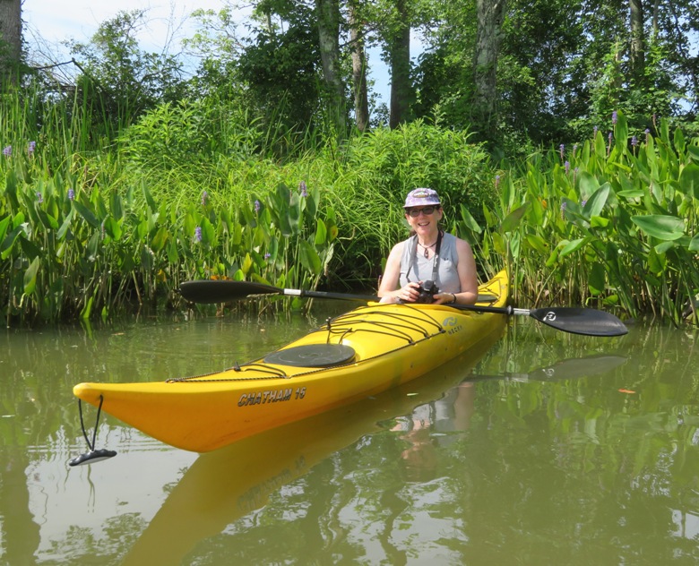 Sara on kayak with pickerelweed flowers behind