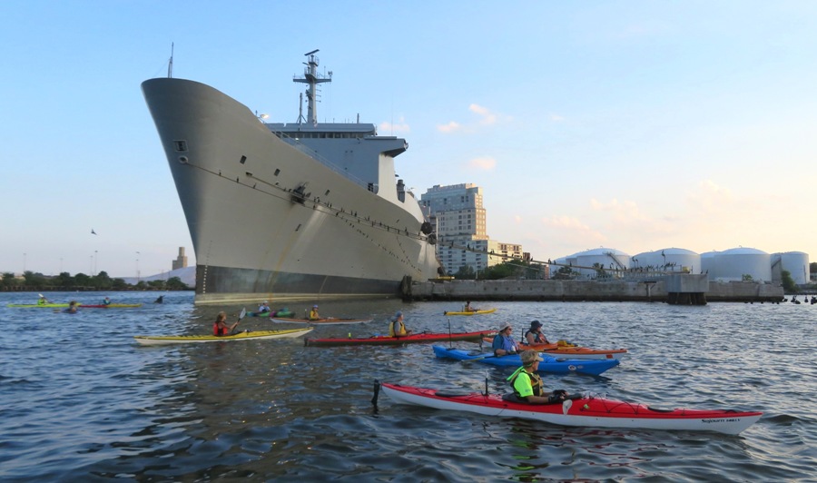 Group of kayakers with big ship in background