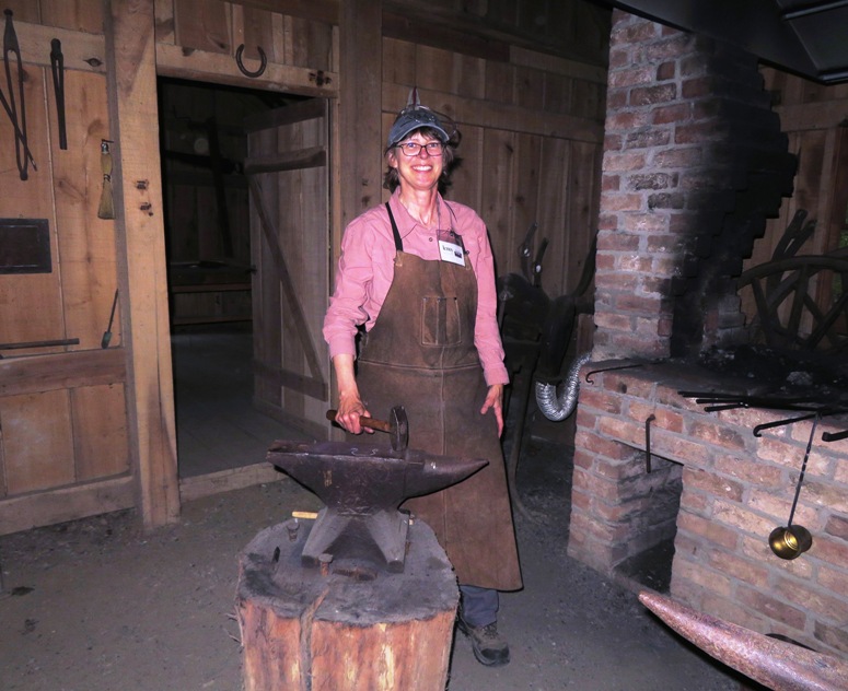 Jenny at the anvil holding a hammer