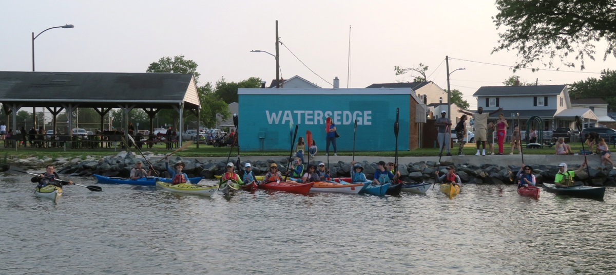 Several kayakers in front of Watersedge sign at park