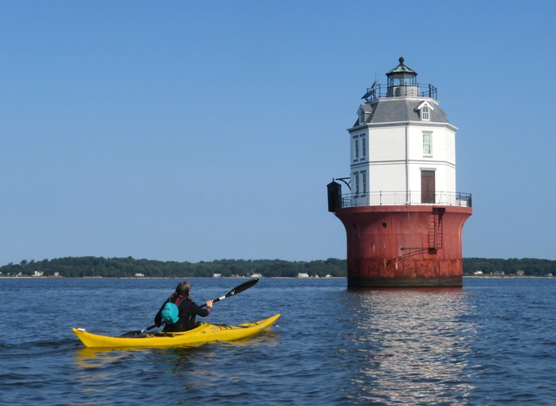 Sara kayaking towards lighthouse with privy on its left side