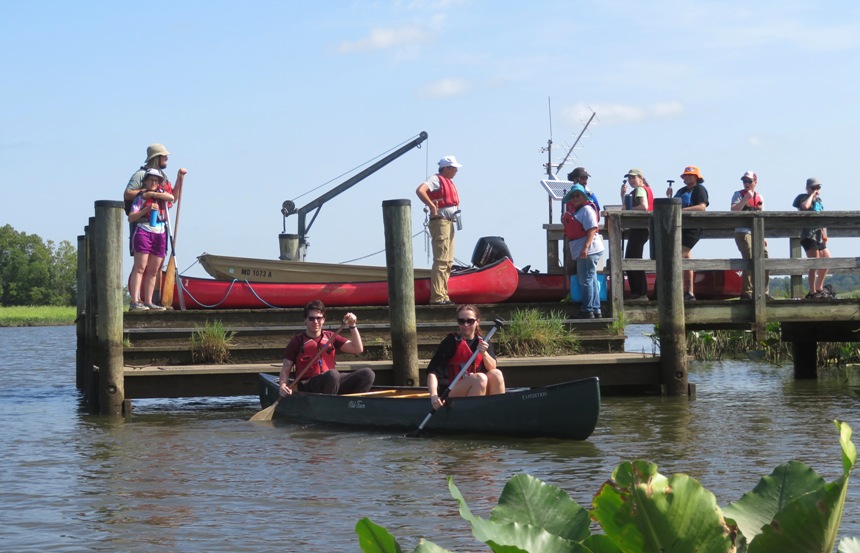 People launching canoes while other wait on the pier