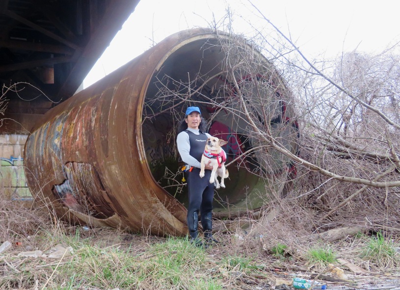 Me holding Daphne with her ears sticking out.  A pipe with ~10 foot diameter lies behind us.