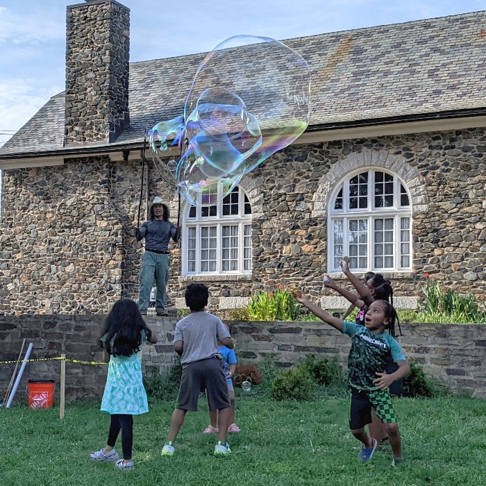 Front view of me making bubbles and kids trying to pop them